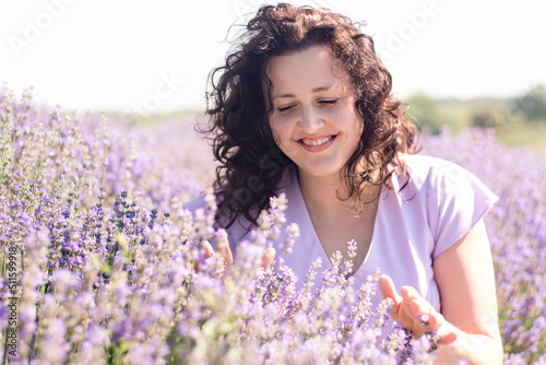 Soft selective focus portrait of a girl enjoying the scent of lavender and her beauty on a sunny day in the field. The girl walks a pink field of flowers. Digital detox, the pleasure of a slow life.