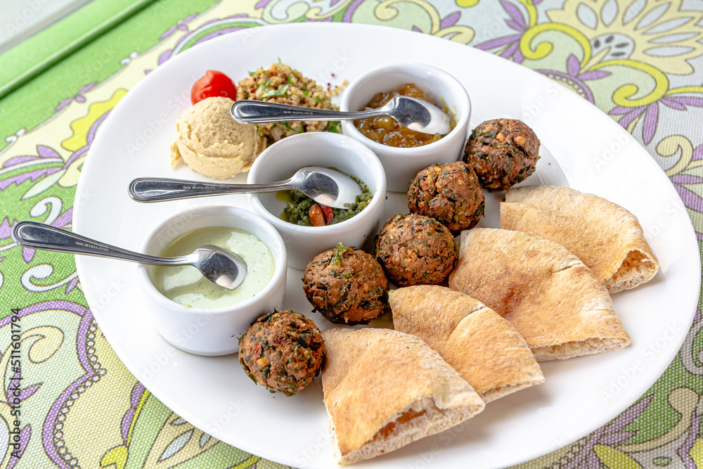 Traditional middle eastern homemade dishes falafel, pita, hummus and chickpea served with vegetables and spices on woodwn table