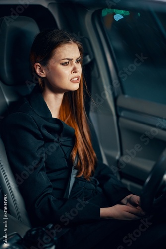 vertical portrait of a frustrated woman sitting in a car at night behind the wheel wearing a seat belt