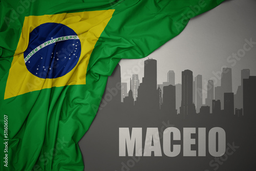 abstract silhouette of the city with text Maceio near waving national flag of brazil on a gray background.