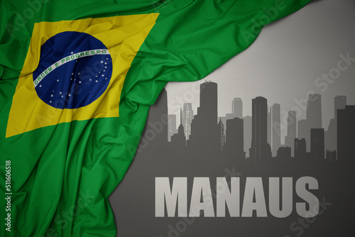 abstract silhouette of the city with text Manaus near waving national flag of brazil on a gray background.