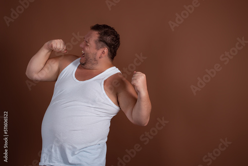 Valokuva An angry fat guy in a white T-shirt screams in disgust against a brown background