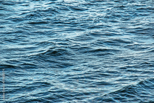 The background of the surface of the water of the river with small ripples and reflections of autumn colors.