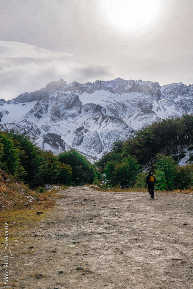 a man walking on a path that leads towards the snowy mountains