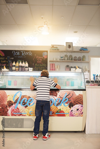 Hes spoilt for choice. Rear view shot of a young boy looking into a freezer at an ice cream store.