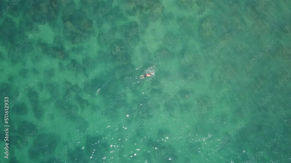 Beautiful aerial view of a man swimming in turquoise water Beautiful aerial view of a man swimming in turquoise water