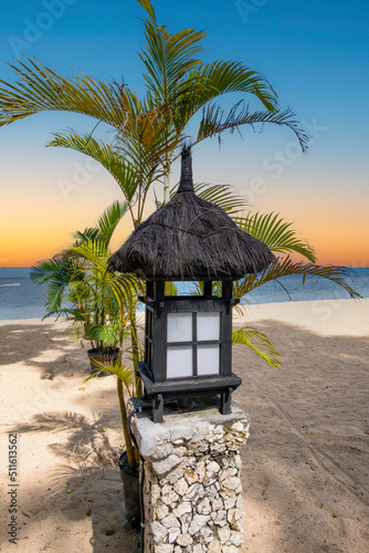 Black wood and straw top lantern on beach at sunset