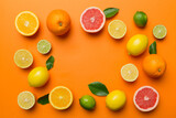 Flat lay of citrus fruits like lime, orange and lemon with lemon tree leaves on light colored background making a frame. Space for text healthy concept