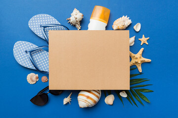 Summer time concept with blank greeting card and blank craft paper on colored background. Seashells from ocean shore in the shape of frame separated with space for text top view