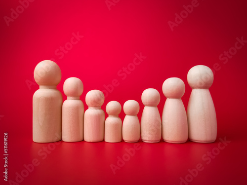 Wooden figures big family lined up according to their respective heights on red background.