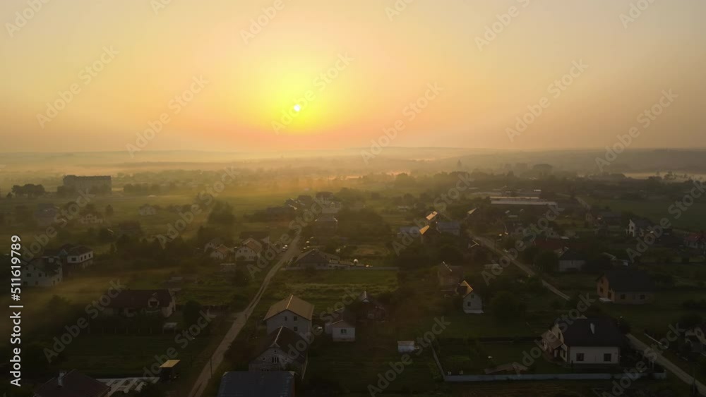 Aerial view foggy sunrise over residential houses in suburban rural area