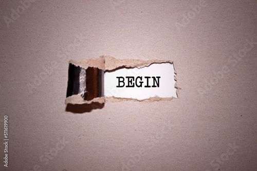 The text Begin appearing behind torn brown paper.