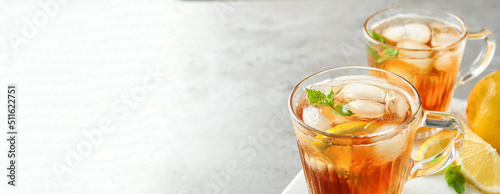 Fotografie Cups of refreshing iced tea on light table, space for text