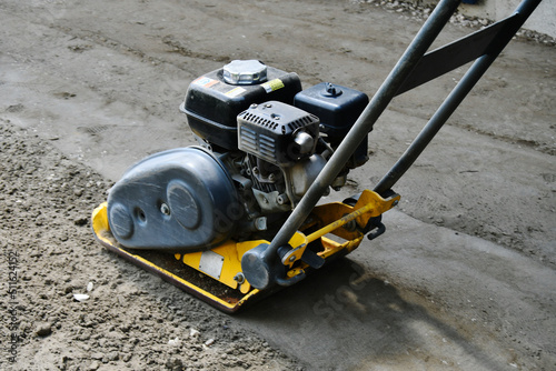 A close up image of a vibrating soil compactor used to compact soil in preparation for paving stones.  photo