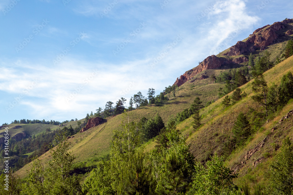 Obraz premium Summer landscape, mountains and rocks against a blue sky with clouds, with copy space. Tourism, active recreation.