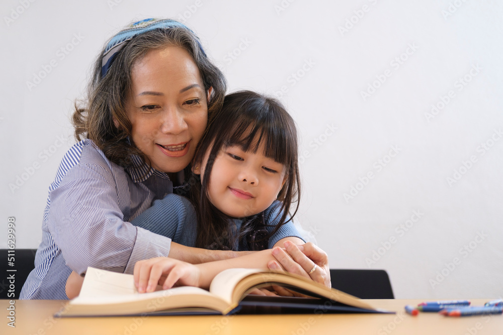 Loving senior grandmother hugging and reading fascinating fairytale to her grandchild. Family holiday and togetherness. Loving senior grandmother hugging and reading fascinating fairytale to her grandchild. Family holiday and togetherness.