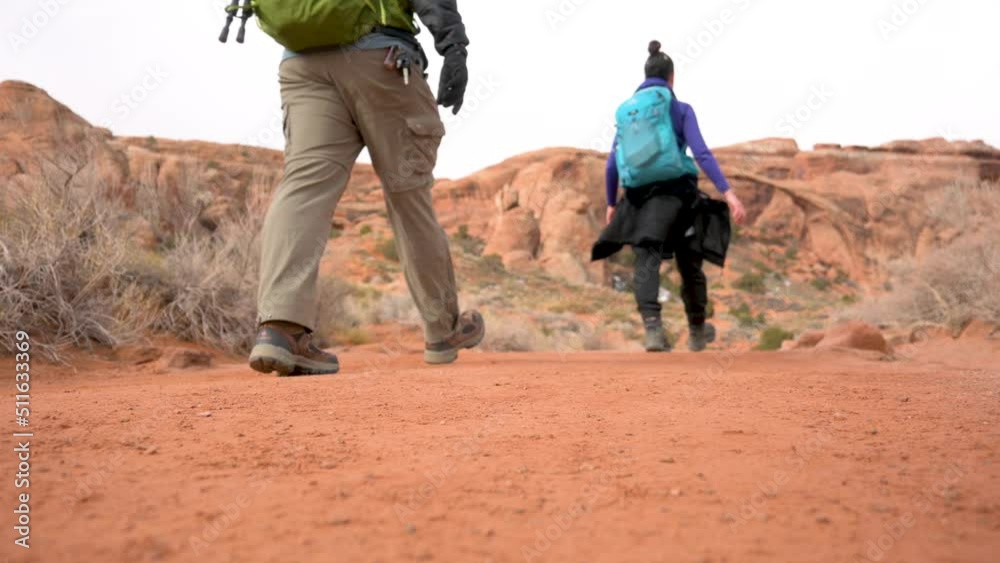Hikers walking toward Landscape Arch on an overcast day in Arches National Park, static Hikers walking toward Landscape Arch on an overcast day in Arches National Park, static