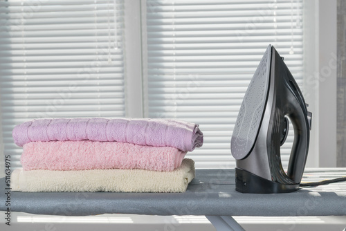 Electric iron and ironed linen on the background of the window.