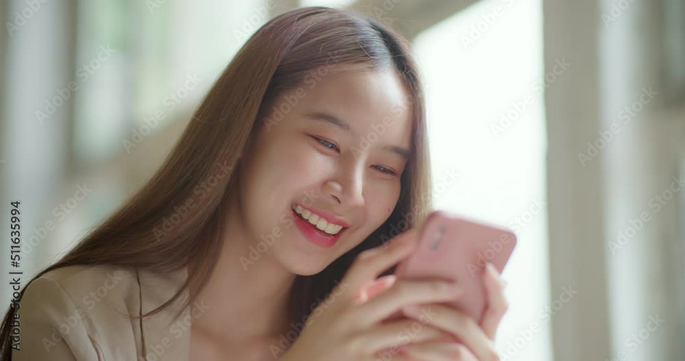Beautiful smiling asian woman sitting at coffee shop using smartphone texting, reading and sharing messages on social media. Attractive Business freelance female holding phone enjoying city lifestyle. Beautiful smiling asian woman sitting at coffee shop using smartphone texting, reading and sharing messages on social media. Attractive Business freelance female holding phone enjoying city lifestyle.