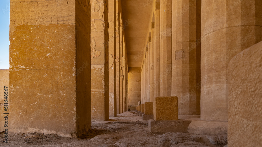 A narrow passage between two rows of columns leads forward. The weathered surface of the floor and walls is visible. Karnak Temple of Luxor. Egypt