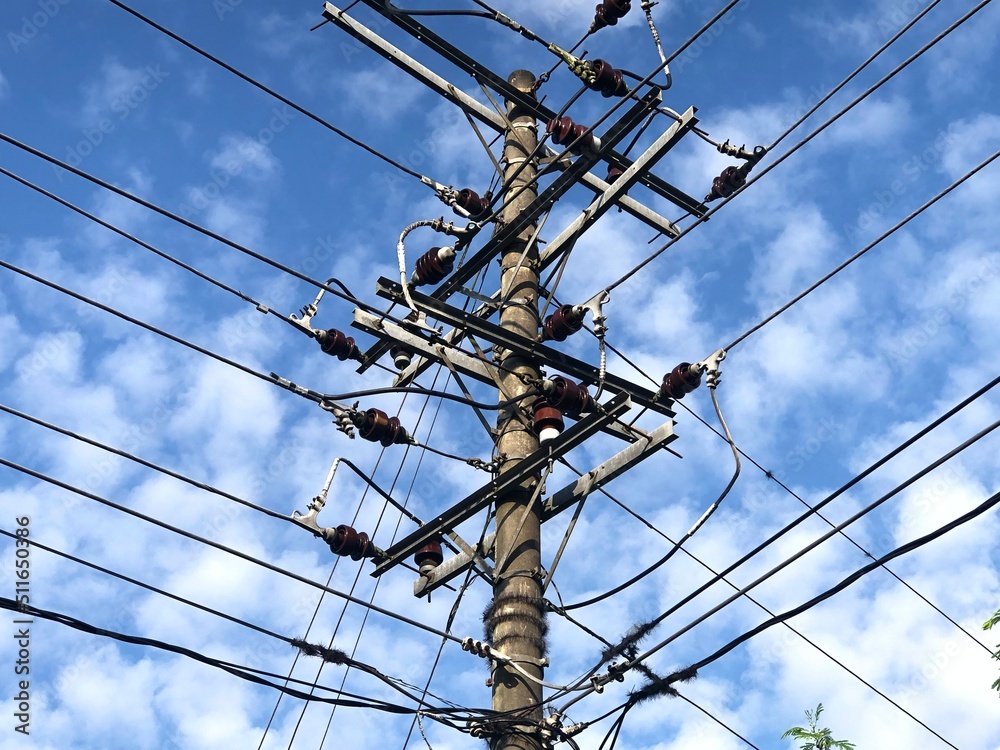 Electricity pole and power line under white cloud and blue sky