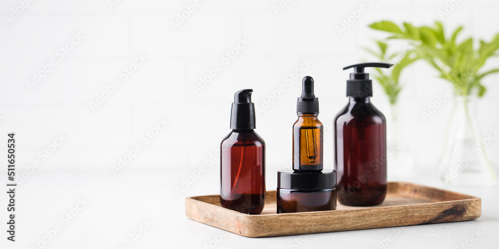 Cosmic jars and dispensers with eco cosmetics on a wooden tray on a light background. Copy space. Cosmic jars and dispensers with eco cosmetics on a wooden tray on a light background. Copy space.