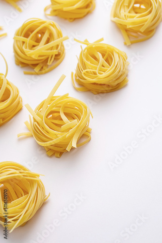 Homemade raw twisted pasta on pink table. Mediterranean food background.