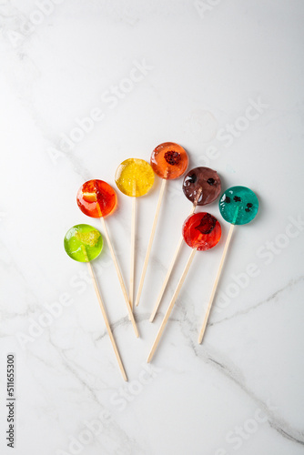 Top view of mealting homemade fruits candy lollipop on light surface