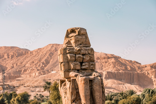 Ancient Egyptian Colossi of Memnon stone pharaoh statue with mountain background at Valley of the Kings in Luxor