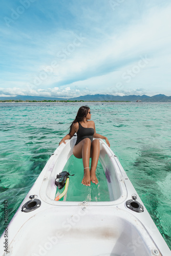 young asian female sitting in a white kayak in the tropical turquoise blue ocean with snorkeling mask