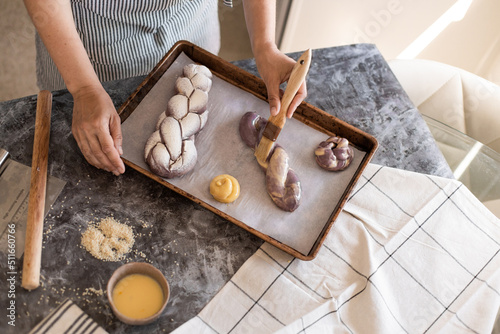 The woman makes challah bread in the kitchen and smears butter with a brush. photo