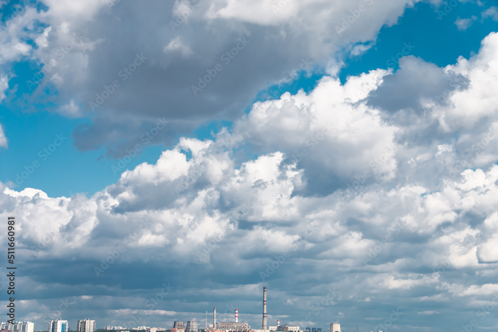Bright beautiful white clouds against the midday blue sky over the city. Bright beautiful white clouds against the midday blue sky over the city.