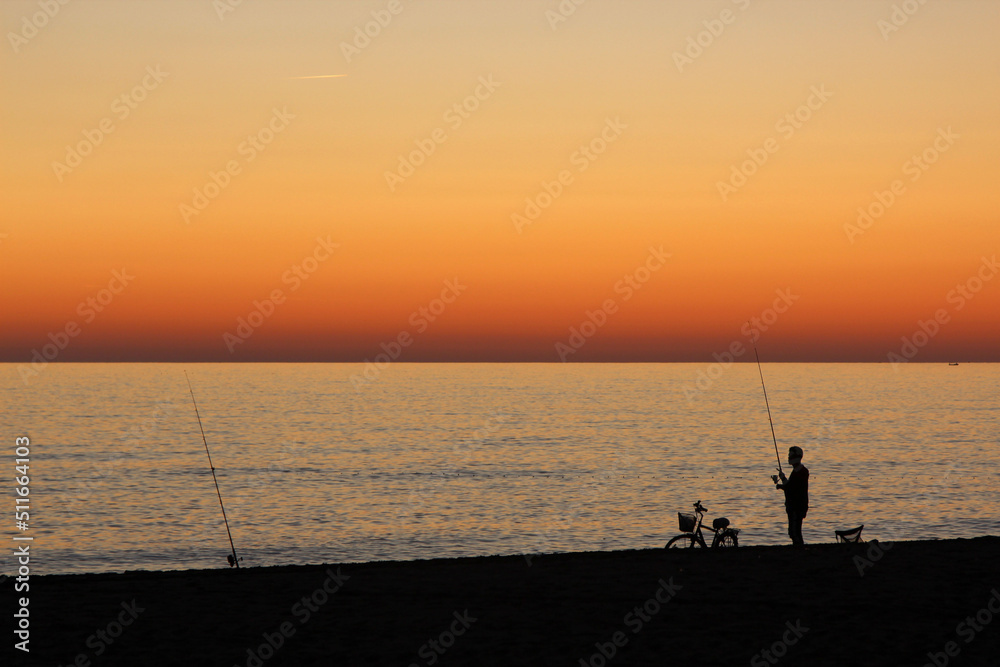 a fisherman at sunset catching fish in the sea