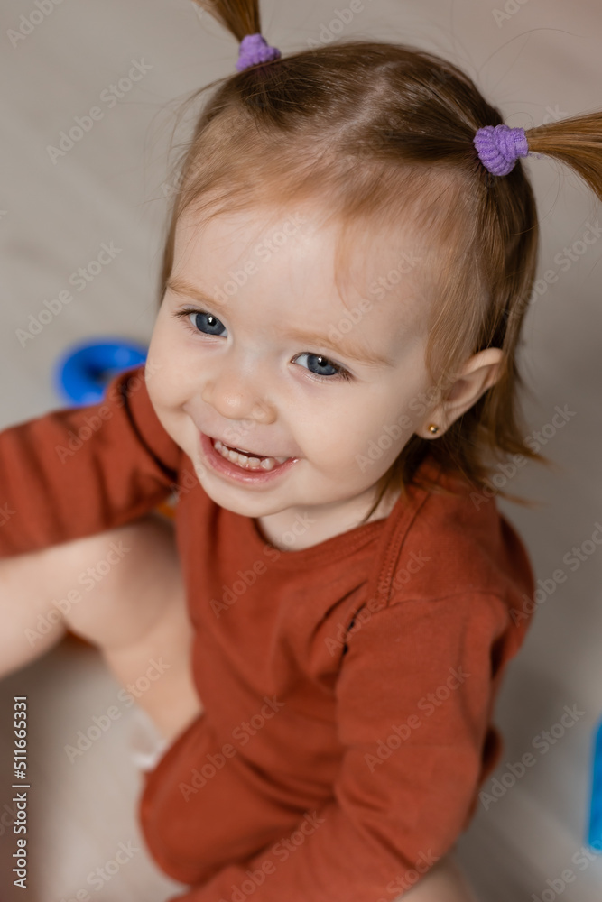 cheerful baby plays with a multi-colored pyramid and other educational toys sitting on the floor cheerful baby plays with a multi-colored pyramid and other educational toys sitting on the floor