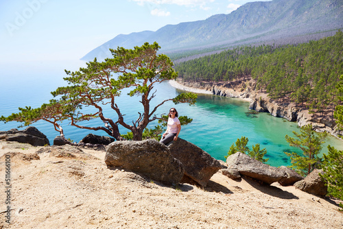 A woman travels on Lake Baikal in the summer. Beautiful view of the lake with turquoise water color, larch, mountains covered with coniferous forest, Sandy Bay.