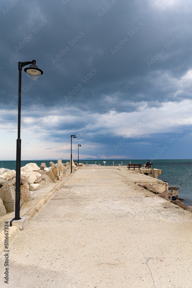 Pier running across the beach with a cloudy background.