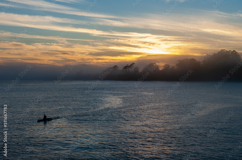 Silhoutte of a person in a kayak peddling in the Santa Cruz bay during sunset. Silhoutte of a person in a kayak peddling in the Santa Cruz bay during sunset.