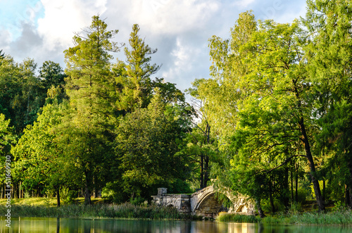 Early autumn, view of the lake with an ancient dilapidated bridge in a cozy wooded park