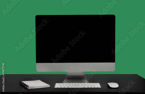 Stylish workspace with blank screen desktop computer at Sea green background.