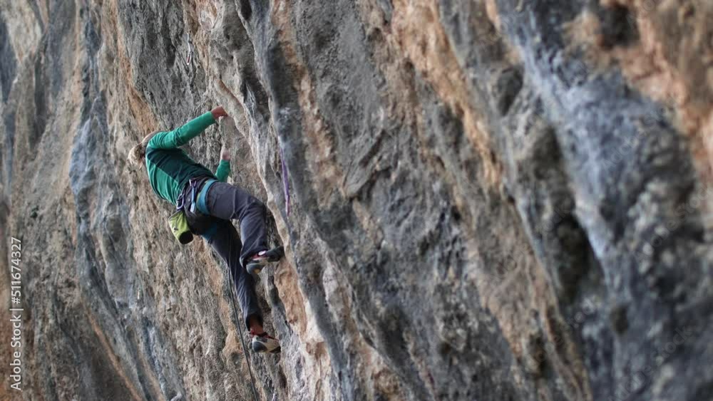 The girl climbs the rock, The climber trains on natural terrain, A woman overcomes a difficult climbing route against the background of a blue sky The girl climbs the rock, The climber trains on natural terrain, A woman overcomes a difficult climbing route against the background of a blue sky