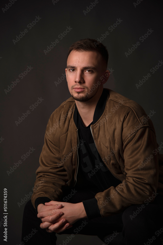 portrait of handsome man sitting on chair in dark studio  