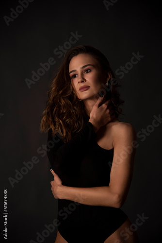 Beautiful sexy woman on black background touching her neck