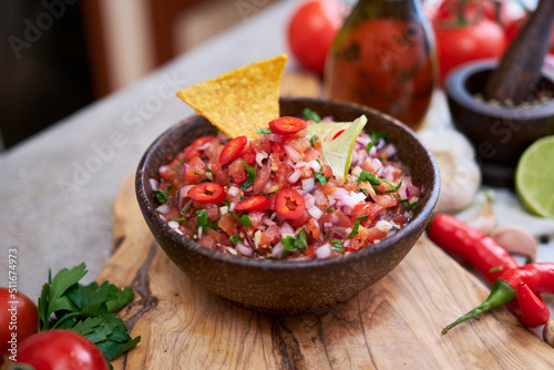 freshly made salsa dip sauce with nacho chips on wooden board