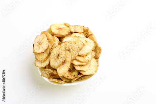 Salty banana chips in bowl on white background.