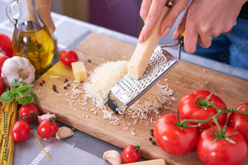 grating parmesan on a wooden gutting board at domestic kitchen