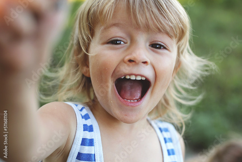 close-up of a blond boy in the sand happily screaming
