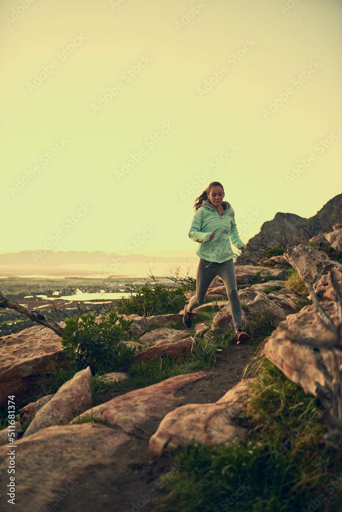 Shes dominating the mountain pass. Full length shot of a sporty young woman hiking on a mountain trail.