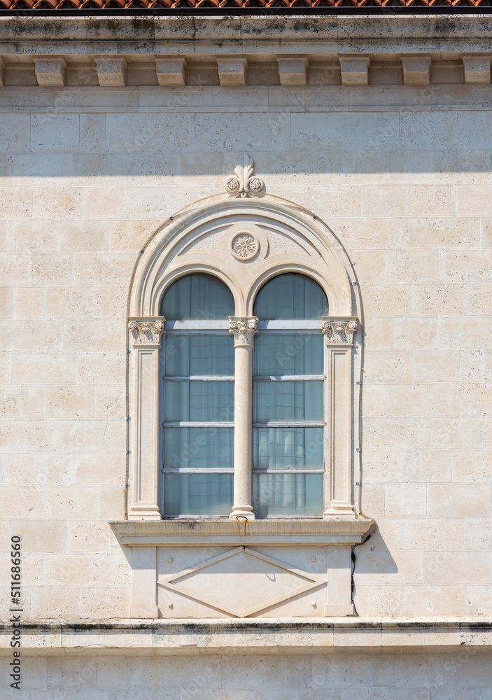 Fragment of the facade of a Mediterranean building with a beautiful window and relief decor