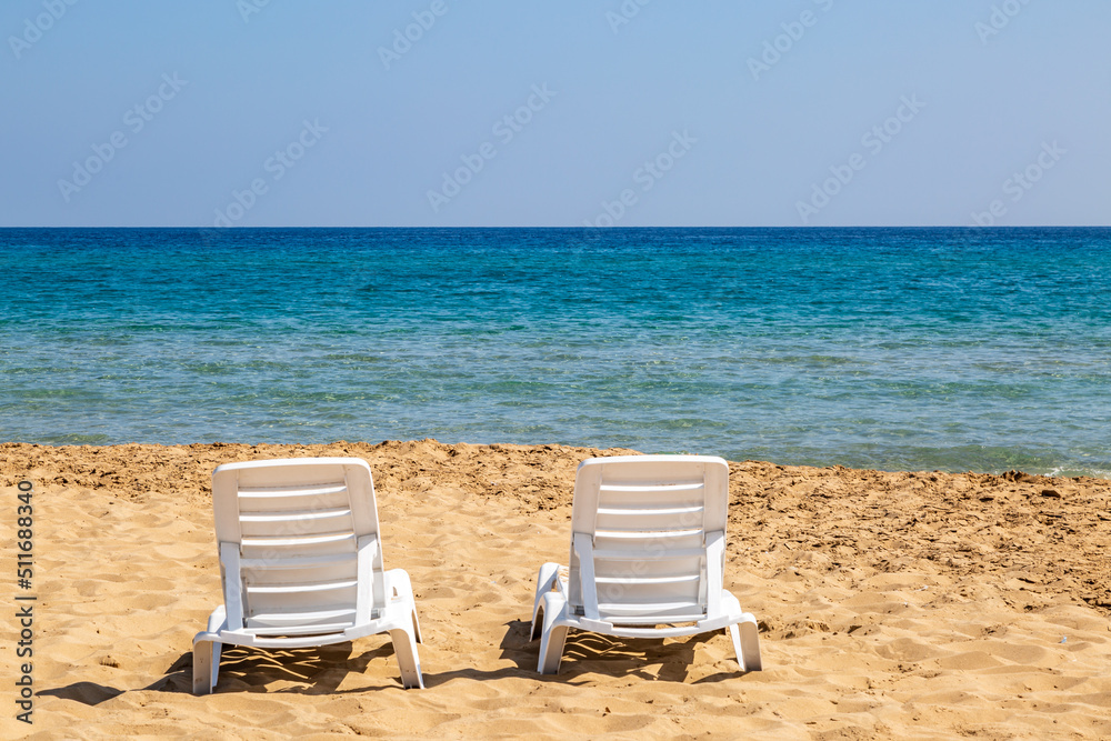 Sunloungers on a sandy beach with a view out to sea, at Golden Beach in Cyprus Sunloungers on a sandy beach with a view out to sea, at Golden Beach in Cyprus