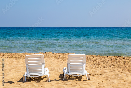Sunloungers on a sandy beach with a view out to sea, at Golden Beach in Cyprus © lemanieh